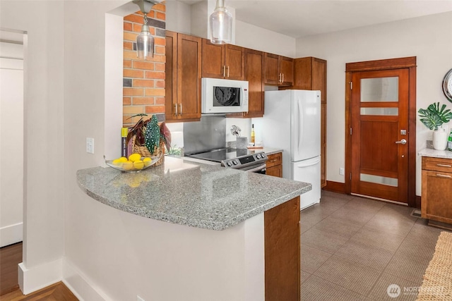 kitchen featuring brown cabinetry, white appliances, baseboards, and light stone countertops