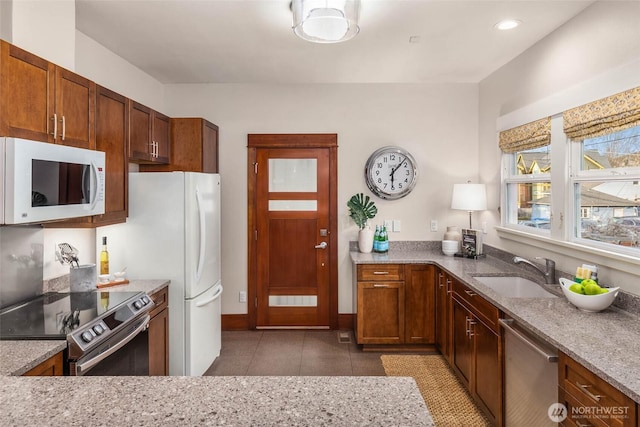 kitchen featuring light tile patterned floors, stainless steel appliances, recessed lighting, a sink, and light stone countertops