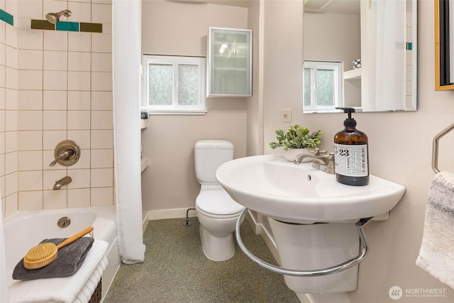 bathroom featuring washtub / shower combination, baseboards, and toilet