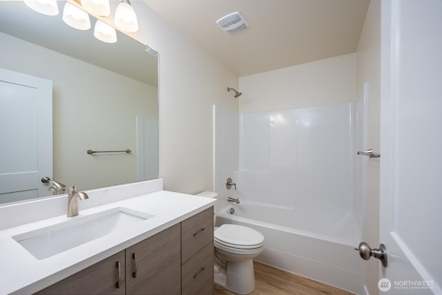 bathroom with toilet, wood finished floors, visible vents, vanity, and shower / washtub combination