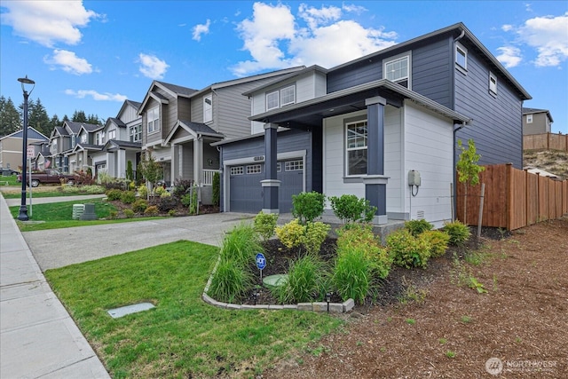 view of front of property with a front yard, fence, a garage, a residential view, and driveway