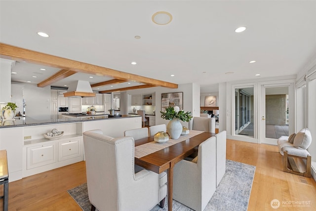 dining space with light hardwood / wood-style flooring and beamed ceiling