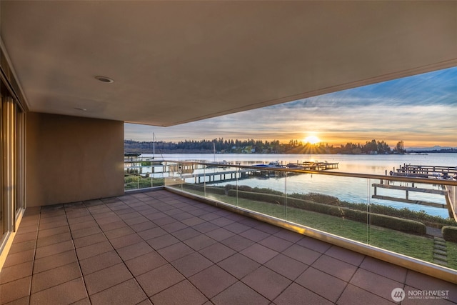 balcony at dusk featuring a water view