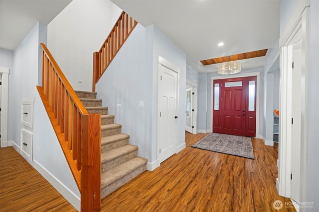 foyer entrance with stairs, baseboards, and wood finished floors