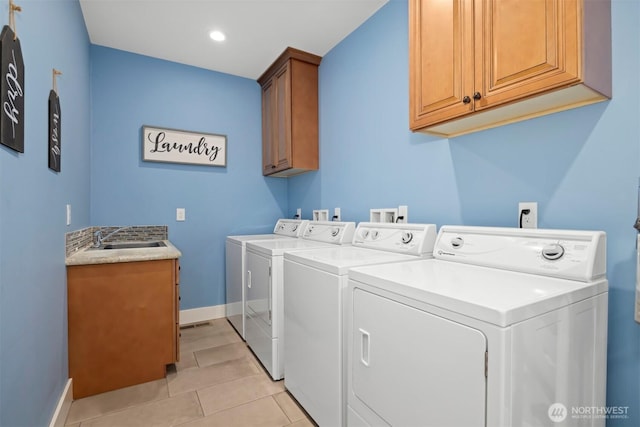 washroom with light tile patterned flooring, a sink, baseboards, washer and dryer, and cabinet space