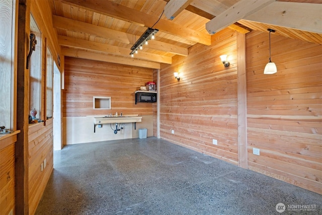 empty room featuring wood ceiling, rail lighting, speckled floor, wood walls, and beam ceiling