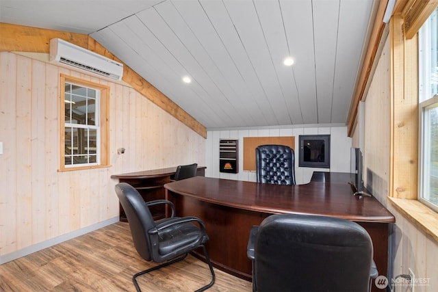 office featuring light wood-style floors, vaulted ceiling, wooden walls, and a wall mounted AC