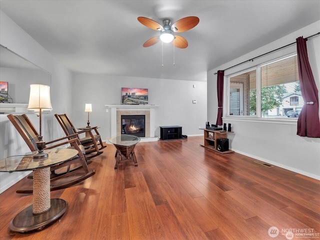 interior space with ceiling fan, hardwood / wood-style flooring, and a tiled fireplace