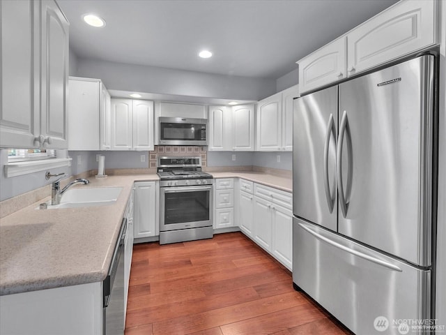 kitchen with white cabinetry, appliances with stainless steel finishes, sink, and light hardwood / wood-style flooring