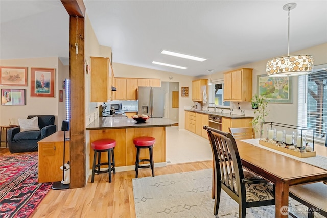 kitchen featuring kitchen peninsula, plenty of natural light, light hardwood / wood-style floors, appliances with stainless steel finishes, and light brown cabinetry