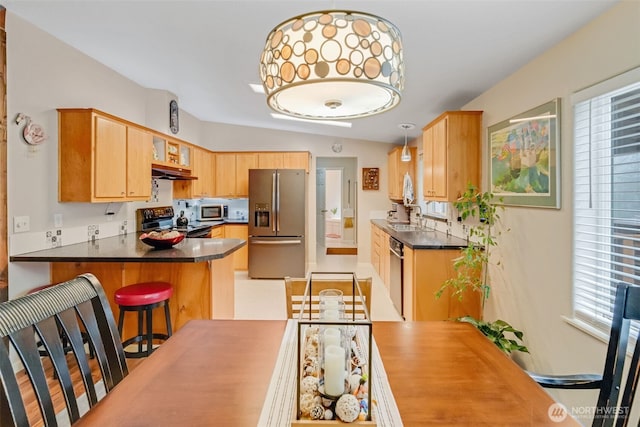 kitchen featuring stainless steel appliances, decorative light fixtures, a breakfast bar, sink, and kitchen peninsula