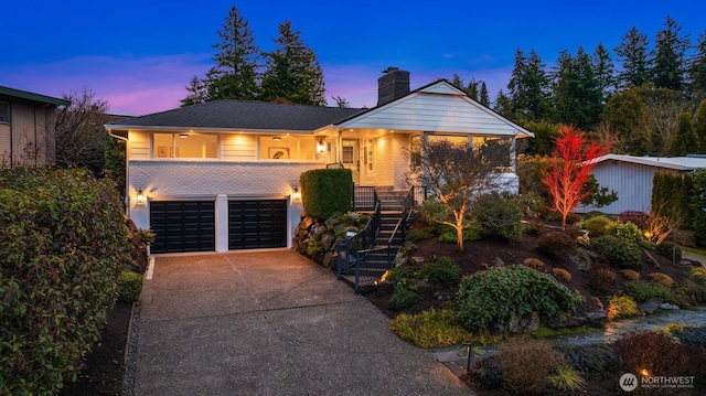 view of front of property featuring driveway, an attached garage, stairs, and a chimney