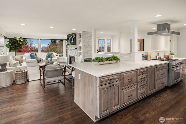 kitchen with dark wood finished floors, open floor plan, high end stainless steel range, island exhaust hood, and light countertops