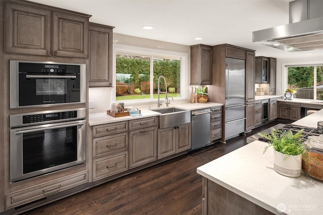 kitchen featuring extractor fan, beverage cooler, a sink, light countertops, and appliances with stainless steel finishes