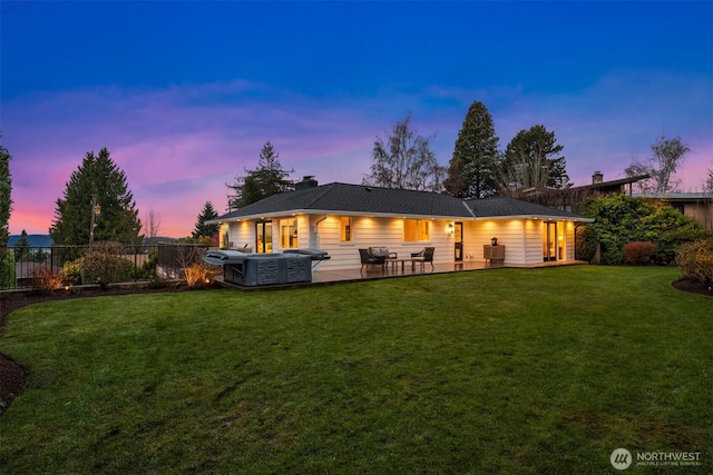 rear view of house with a hot tub, a lawn, a fenced backyard, a chimney, and a patio area