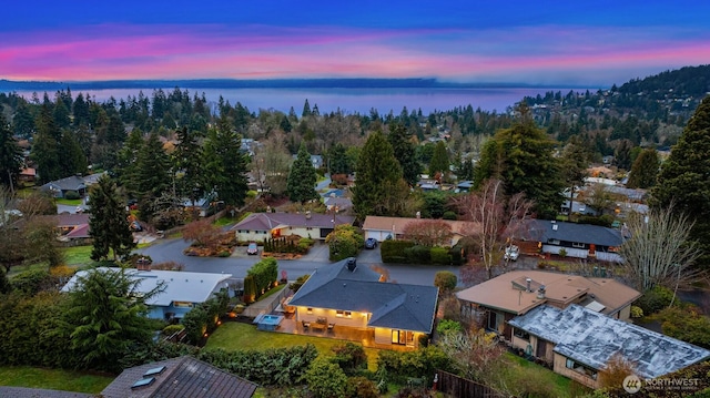 aerial view at dusk with a water view and a residential view