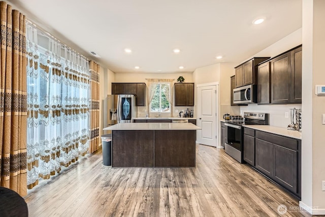 kitchen with light hardwood / wood-style floors, a kitchen island, stainless steel appliances, and dark brown cabinetry