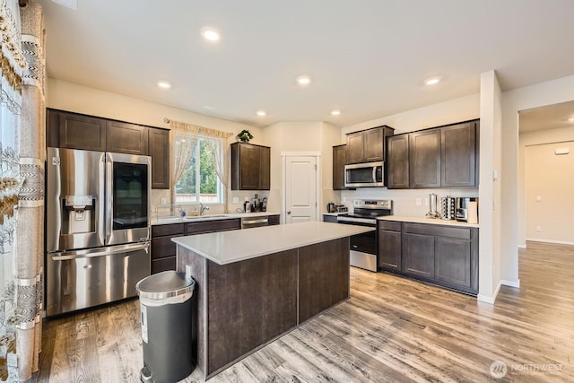 kitchen with dark brown cabinetry, stainless steel appliances, a kitchen island, and sink