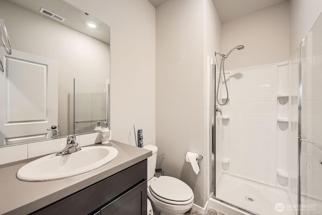 bathroom featuring vanity, a shower with door, and toilet