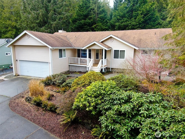 ranch-style house with a chimney, a porch, a shingled roof, an attached garage, and driveway