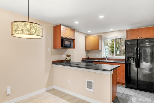 kitchen featuring decorative light fixtures, sink, black appliances, and kitchen peninsula