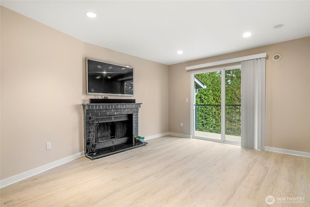 unfurnished living room featuring a brick fireplace and light hardwood / wood-style flooring