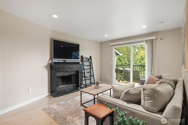 living room featuring light hardwood / wood-style floors and a brick fireplace