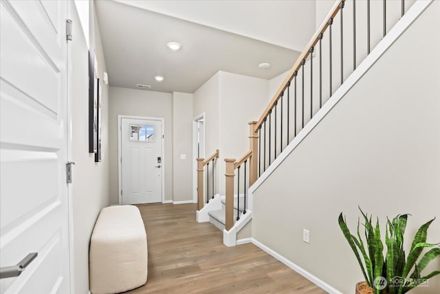 foyer entrance featuring stairs, visible vents, light wood-style flooring, and baseboards