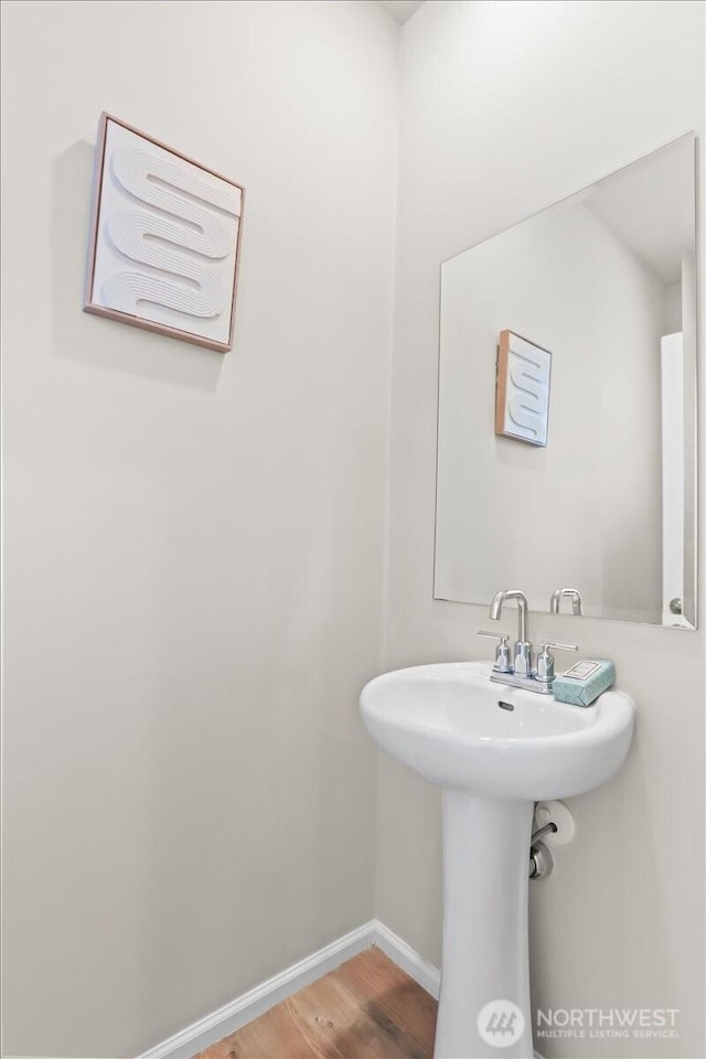 bathroom with a sink, baseboards, and wood finished floors