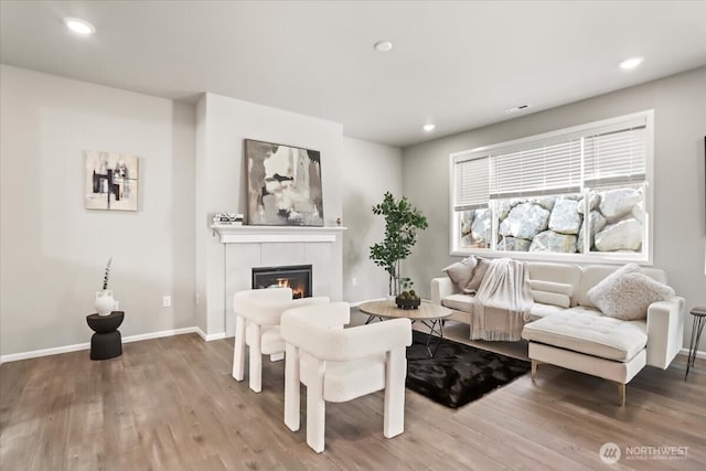 living area featuring recessed lighting, baseboards, wood finished floors, and a tile fireplace