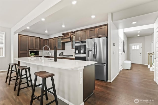 kitchen featuring appliances with stainless steel finishes, light countertops, dark wood-type flooring, and a sink