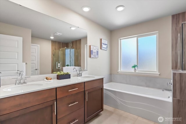 bathroom featuring a bath, a shower stall, double vanity, and a sink