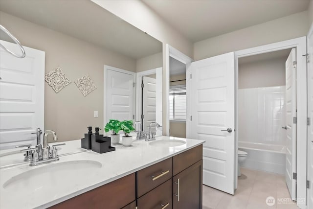 bathroom featuring tile patterned flooring, a sink, toilet, and double vanity