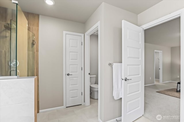 bathroom with toilet, a stall shower, and baseboards