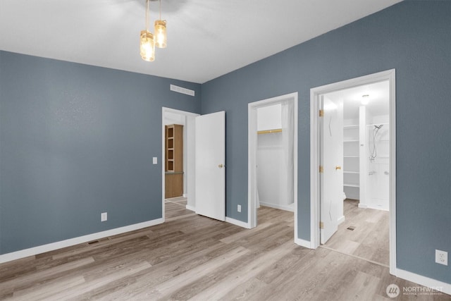 unfurnished bedroom featuring light wood-style floors, visible vents, and a spacious closet