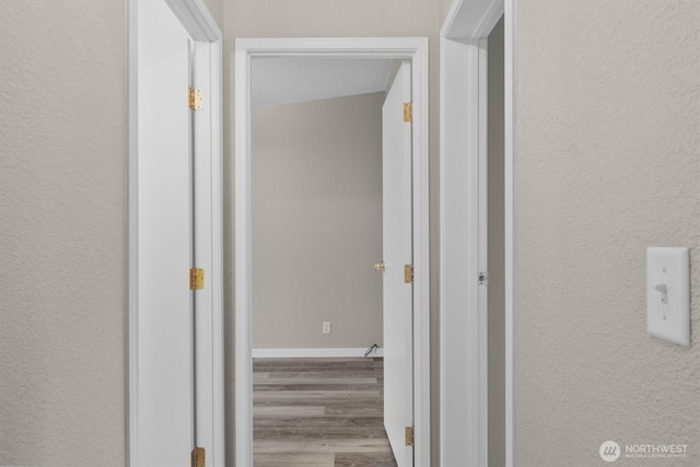 corridor with light wood-style floors and baseboards