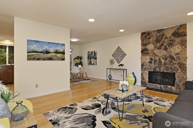 living room featuring light wood-type flooring and a stone fireplace