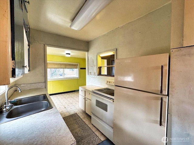 kitchen featuring light countertops, white appliances, a sink, and white cabinetry