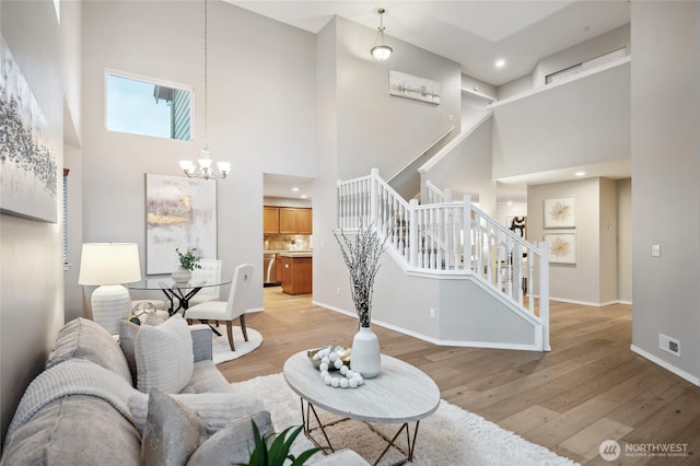 living room featuring light wood-type flooring, a high ceiling, and an inviting chandelier