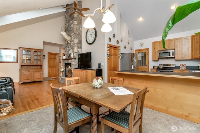 dining space with a stone fireplace, high vaulted ceiling, recessed lighting, and ceiling fan