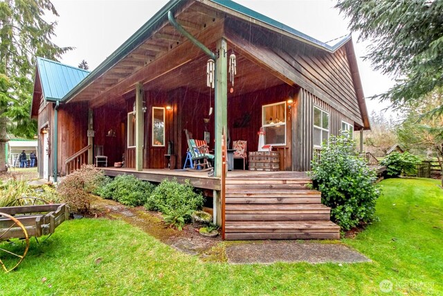 rear view of house featuring a lawn, a porch, and metal roof