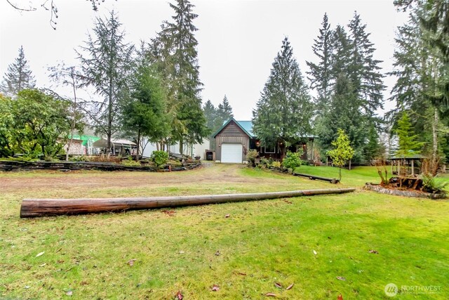 view of yard featuring a garage and dirt driveway