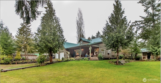 back of property featuring a chimney, a lawn, metal roof, and a garage