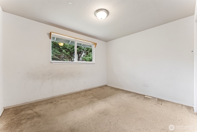 carpeted empty room featuring baseboards