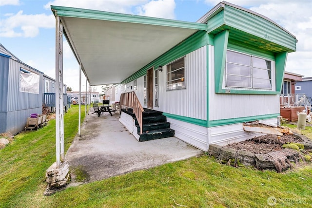 view of front of home with a carport, a front yard, and a patio area