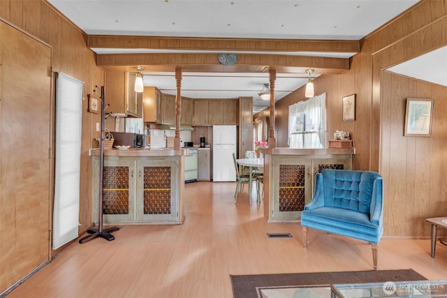 interior space with light wood-style floors, visible vents, wood walls, and beamed ceiling