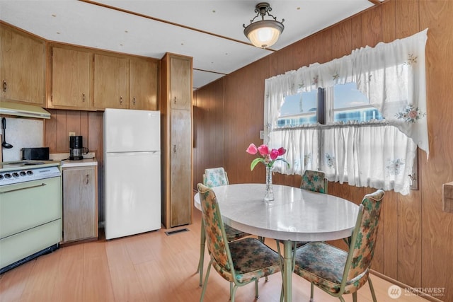 kitchen featuring brown cabinets, light countertops, wooden walls, white appliances, and extractor fan