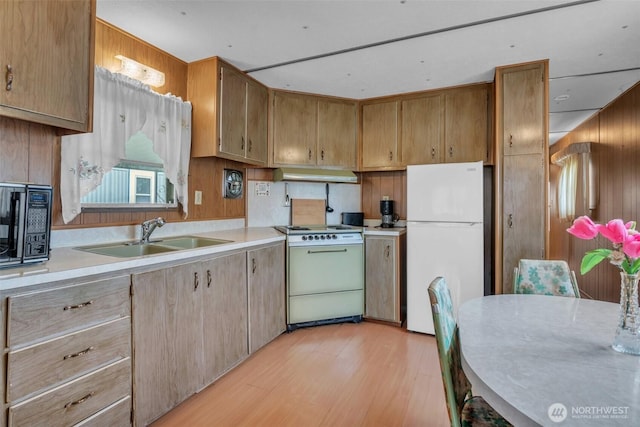 kitchen featuring light countertops, light wood-style flooring, a sink, white appliances, and under cabinet range hood