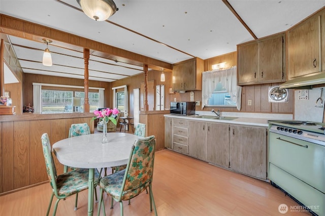 kitchen featuring black microwave, stove, a sink, light countertops, and pendant lighting