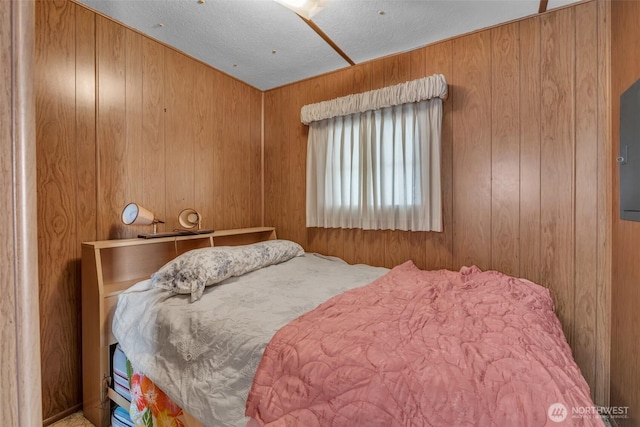 bedroom featuring wooden walls and a textured ceiling